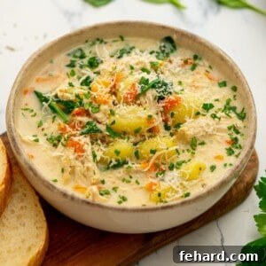 Bowl of creamy Instant Pot Chicken Gnocchi Soup next to crusty bread and fresh parsley.