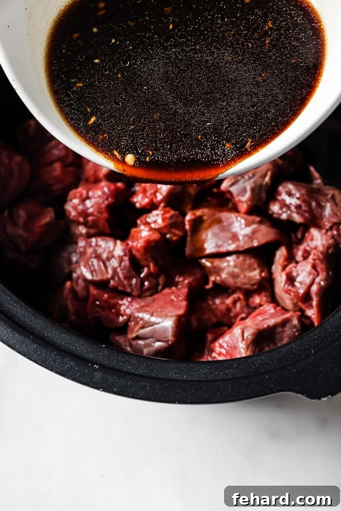 The sauce is poured over pieces of beef in a slow cooker. 