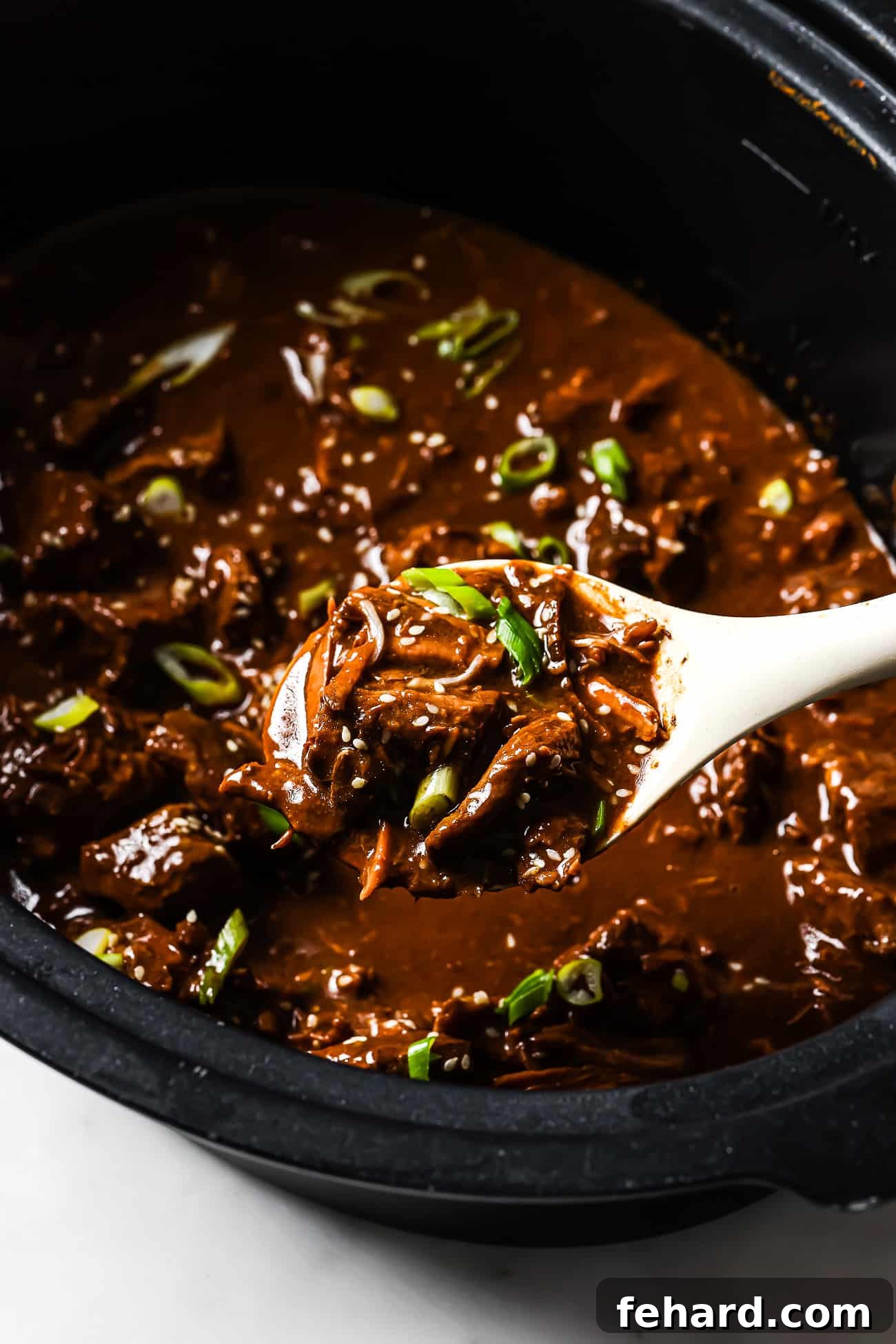 An overhead view of slow cooker Korean beef being dished out of a slow cooker. 