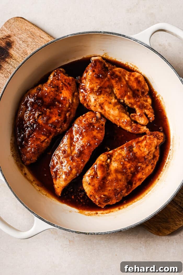 Sticky Honey Garlic Chicken Breast 8 Honey garlic chicken breasts fully covered in the rich, sticky sauce within a white skillet, bubbling gently.