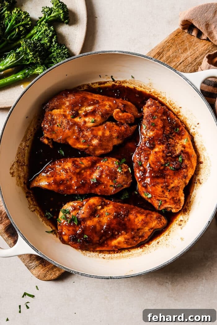 Sticky Honey Garlic Chicken Breast 9 Honey garlic chicken breast garnished with fresh parsley and sesame seeds in a white skillet, with broccoli on the side, ready to serve for dinner.