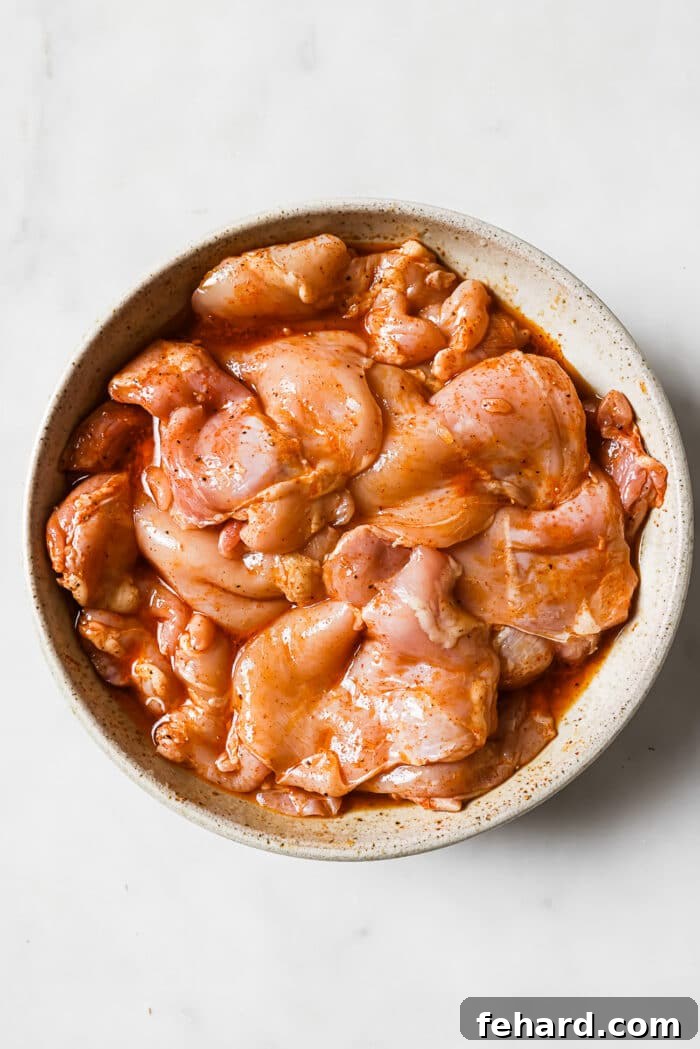 Flavor-Packed Homemade Chicken Tacos 5 Chicken thighs coated with marinated in a large white bowl.