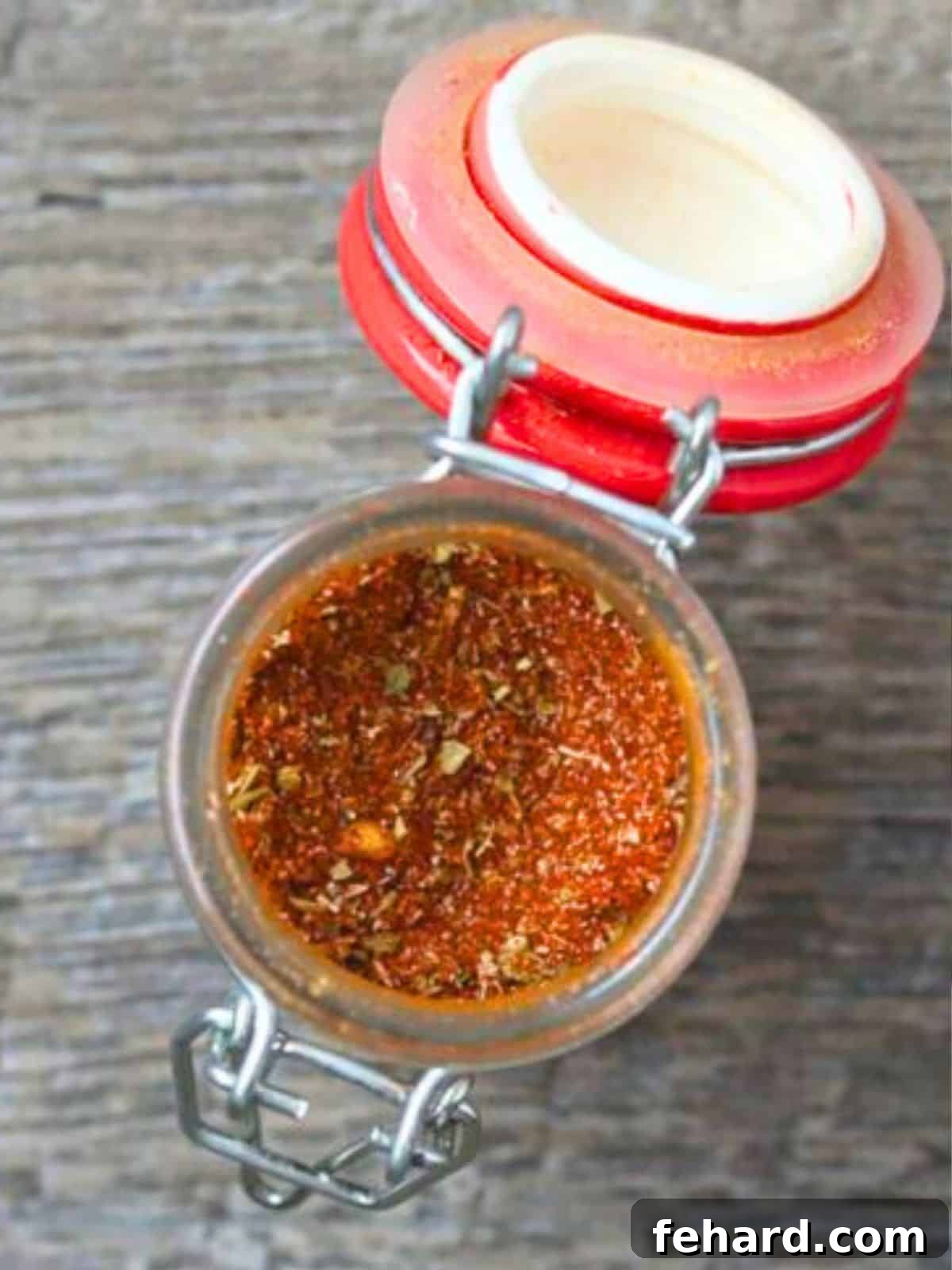 Jar of homemade taco seasoning in a small spice jar, showcasing the rich colors of the freshly mixed spices. The jar sits on a rustic wooden surface, ready for use.