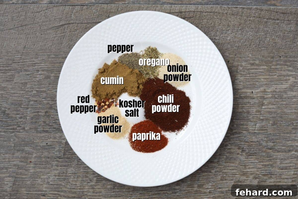 Various essential spices for taco seasoning laid out on a counter, including chili powder, paprika, salt, pepper, cumin, onion powder, garlic powder, and red pepper flakes, each clearly labeled.