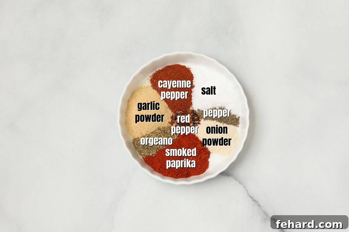 Labeled ingredients for making Cajun seasoning laid out on a kitchen counter: garlic powder, onion powder, oregano, smoked paprika, salt, black pepper, red pepper flakes, and cayenne pepper.