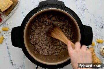 Wooden spoon scraping bottom of inner pot after adding white wine to deglaze inner pot.