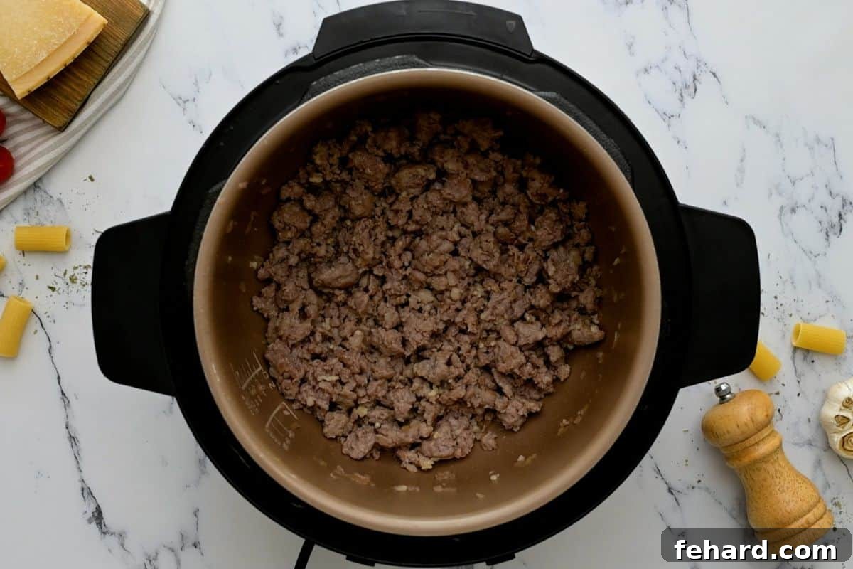 Browned Italian Sausage and sautéed onions in the Instant Pot inner pot.