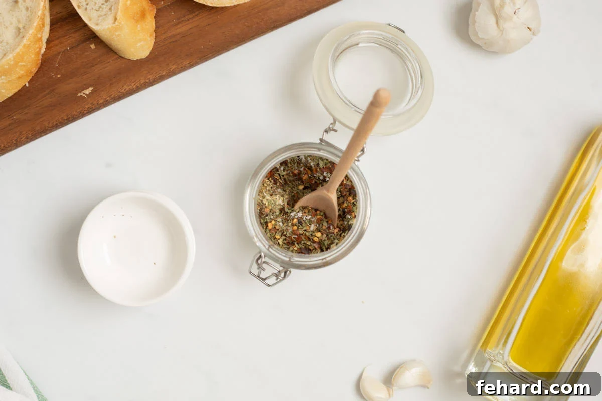 Dried Spices for Italian olive oil bread dip in small glass jar with wooden spoon.
