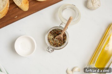 Dried Spices for Italian olive oil bread dip in small glass jar with wooden spoon.