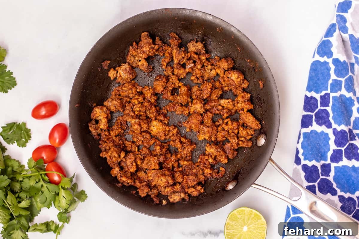 Taco Meat in skillet with cilantro and lime on the side. 