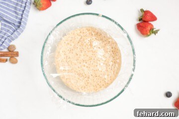 Prepared tapioca pudding in heat-safe bowl with layer of plastic wrap over the top of the surface of the pudding.