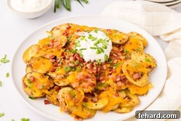 Loaded Irish Potato Nachos made with crispy baked potato slices topped with cheese and bacon served on white plate.