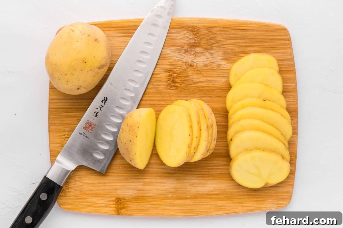 Potato Nacho Recipe Preparation Yukon gold potatoes on wooden cutting board being cut into ¼-inch thick slices, demonstrating the ideal thickness for crispy Irish Nachos.