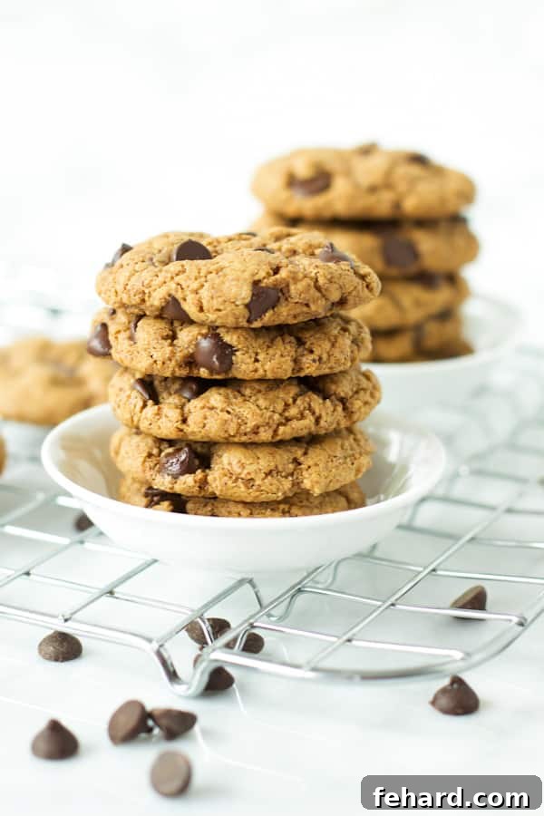 A plate of gluten-free chocolate chip cookies, with one cookie broken in half to reveal its soft, chewy interior.