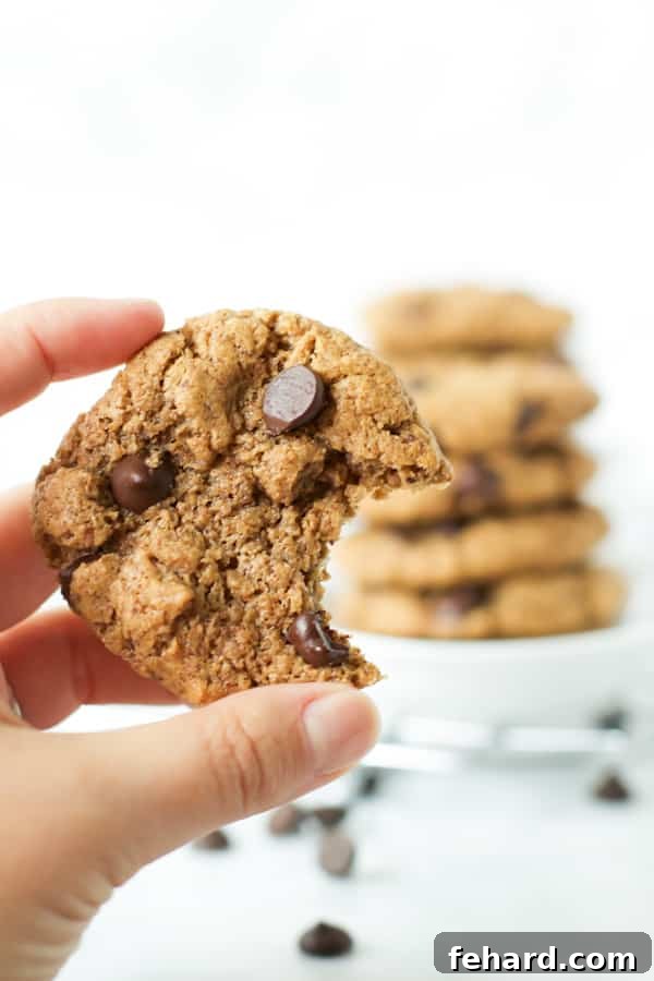 A close-up of a gluten-free chocolate chip cookie with a bite taken out, revealing its soft, gooey interior and melted chocolate.