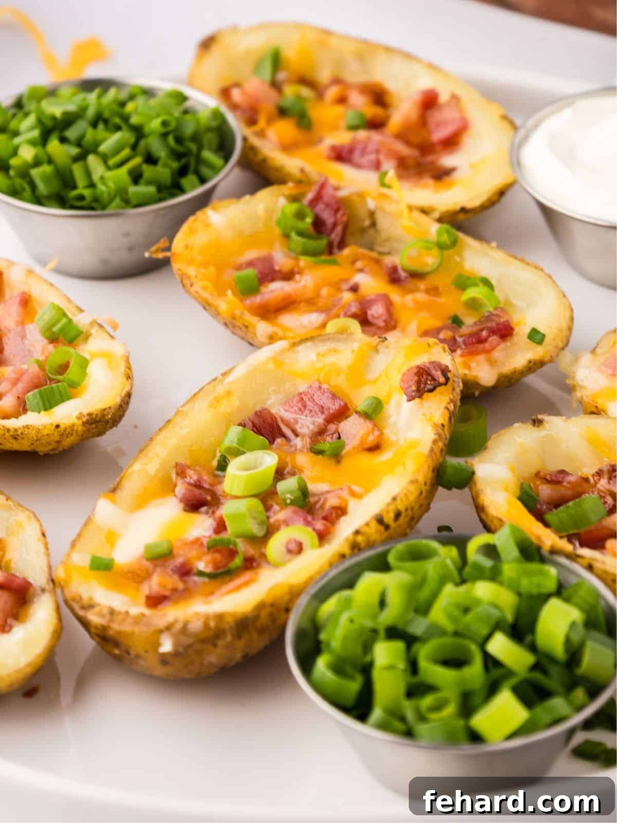 Crispy air fryer potato skins on a white serving platter next to small bowls of fresh green onions and sour cream, ready to be enjoyed.