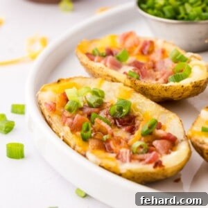 Crispy air fryer potato skins on white serving platter with small dishes of green onions, sour cream, and bacon for topping.