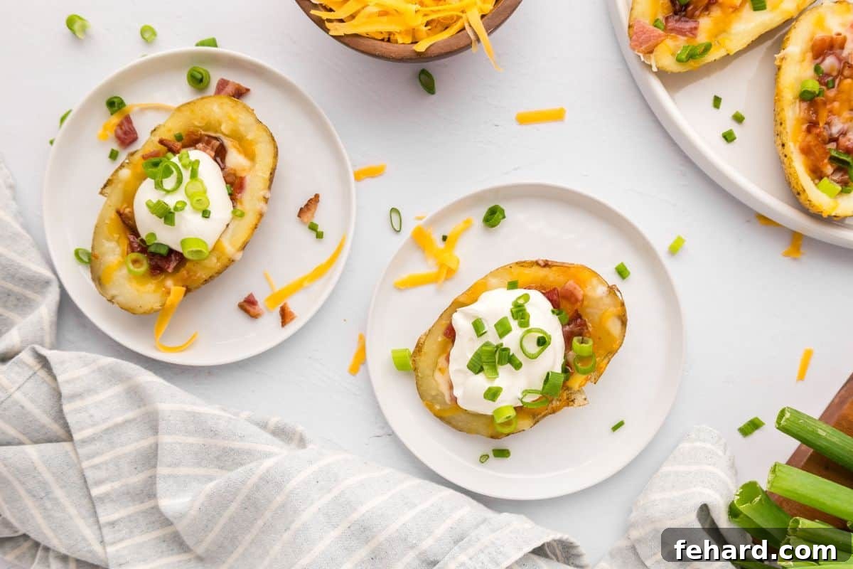 Crispy air fryer potato skins arranged on white plates, garnished with green onions and served with sour cream and extra bacon in the background.