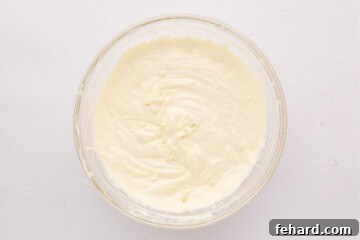 Zesty Lemon Cheesecake Bars 6 Cream cheese, sour cream, eggs, and lemon mixed together in mixing bowl.