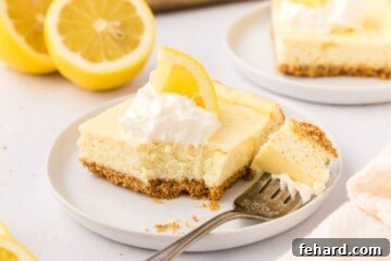 Zesty Lemon Cheesecake Bars 10 Slice of lemon cheesecake bars with fork taking bite out of bar topped with whipped cream and sliced lemon.