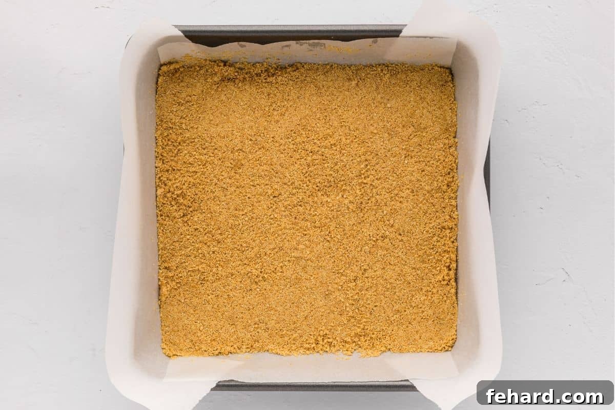 Cheesecake Bars with Graham Cracker Crust Graham cracker crust pressed into 8x8 baking pan lined with parchment paper.