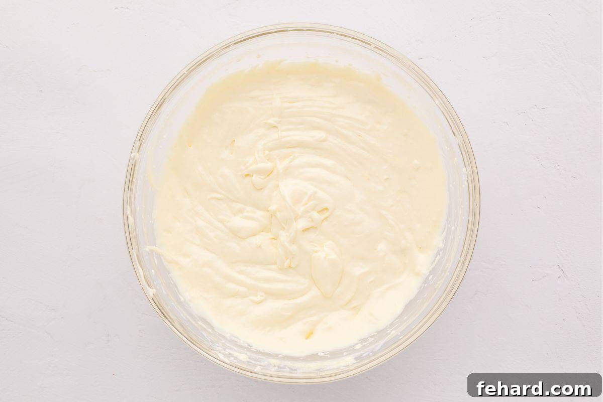 Creamy Lemon Cheesecake Bars Cream cheese, sour cream, eggs, and lemon mixed together in mixing bowl.