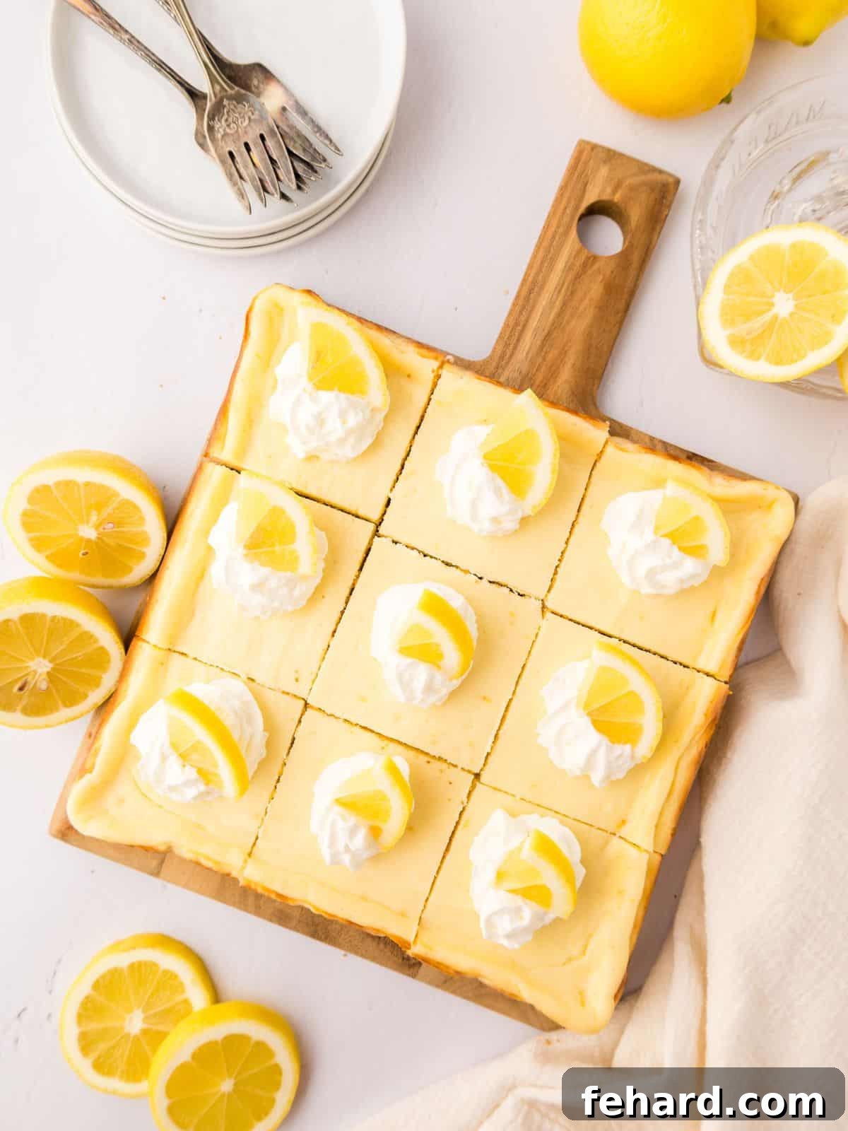 Lemon Bars with Cream Cheese Baked Lemon Cheesecake Bars on wooden platter cut into 12 pieces and topped with dollops of whipped cream and lemon wedges.