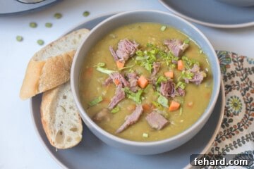 Hearty Instant Pot Split Pea Soup 8 Bowl of Instant Pot split pea soup topped with diced ham and carrots served next to crusty bread.