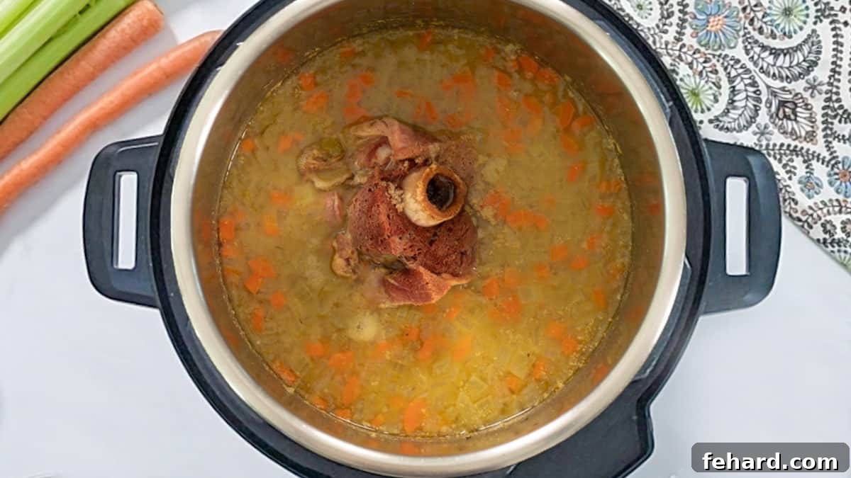 Cooked Split Pea Soup in Instant Pot The Instant Pot, after successfully cooking, reveals perfectly tender split peas in a rich, savory broth, with the ham bone still nestled within, ready for the next step.