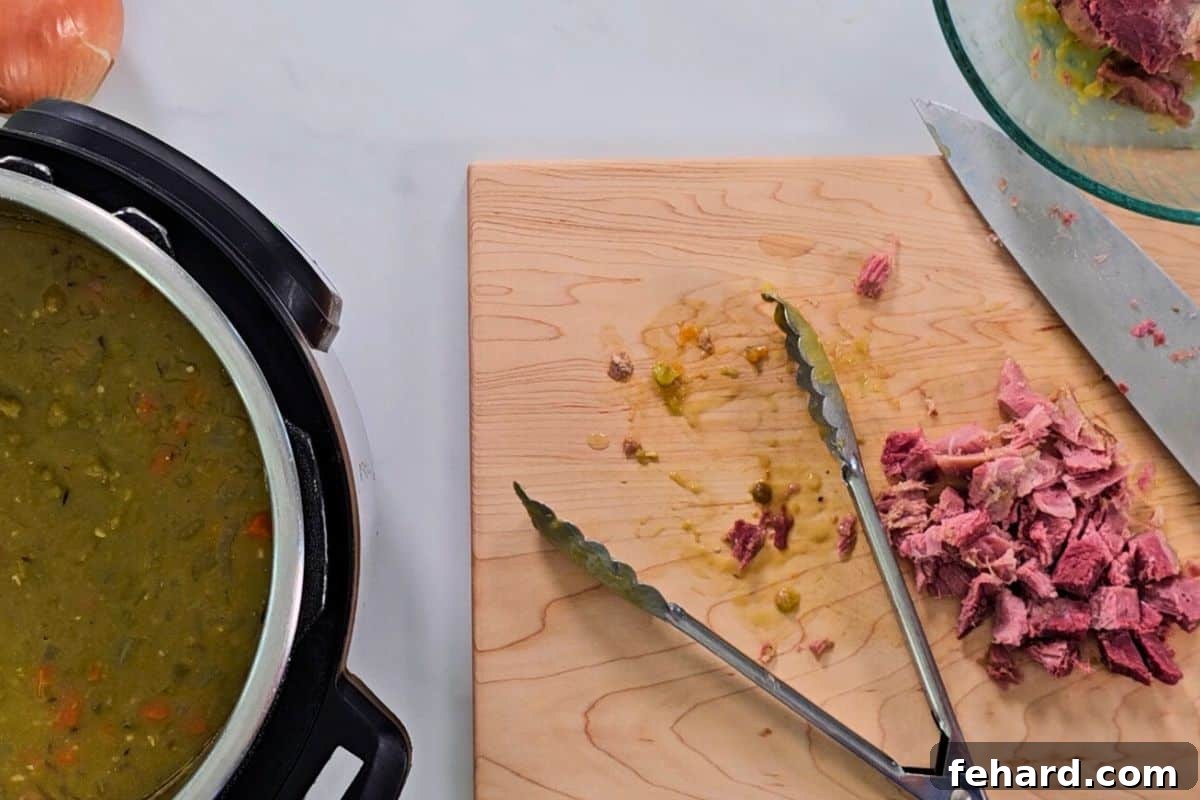 Adding Ham to Split Pea Soup Cooked split pea soup in the Instant Pot's inner pot, with a cutting board displaying diced ham removed from the bone, ready to be stirred back into the soup.