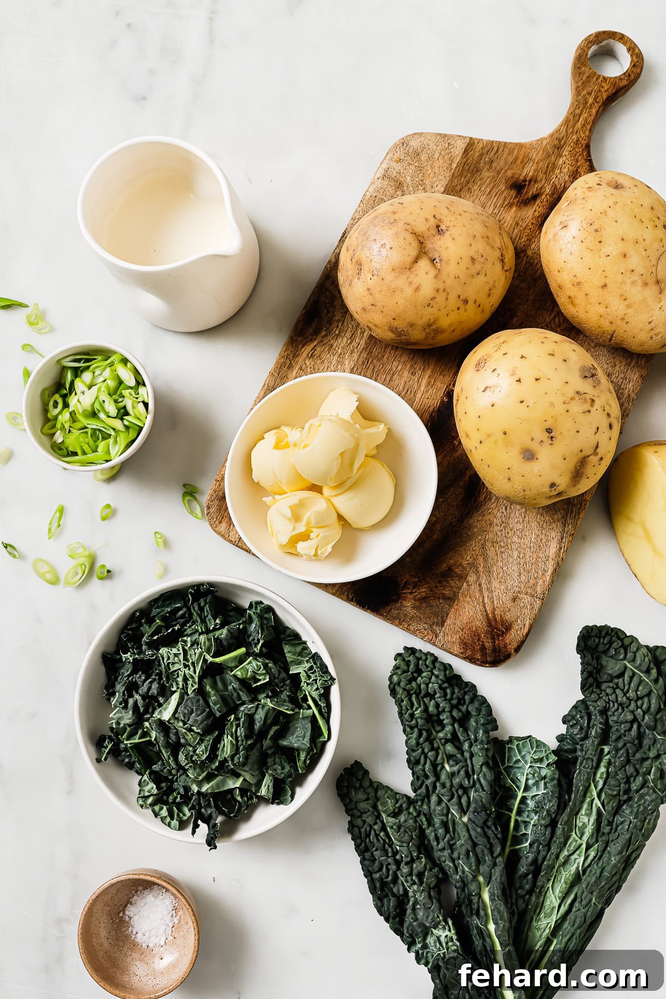 Irish Comfort Colcannon 3 Colcannon ingredients in small bowls on a wooden cutting board and white countertop.