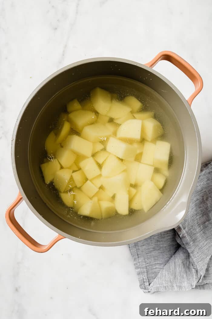 Irish Comfort Colcannon 4 Diced potatoes in a large pot of water on a white countertop.