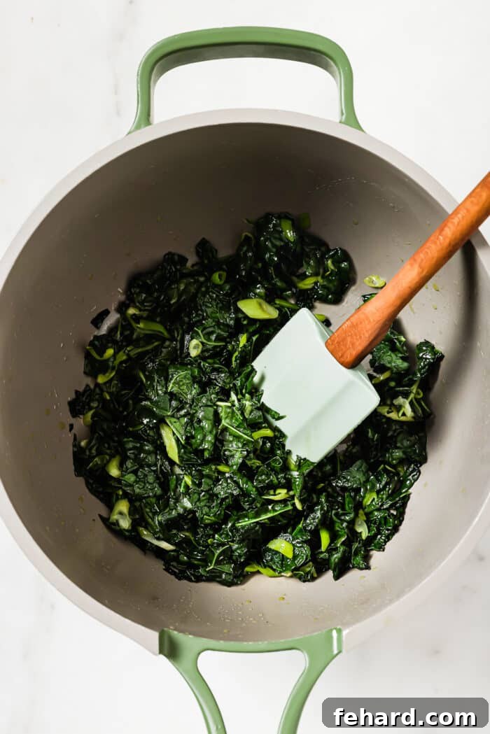 Irish Comfort Colcannon 5 Wilted kale and green onions in a skillet on a white countertop.