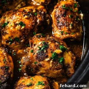 A plate of slow cooker chicken thighs, garnished with fresh parsley.