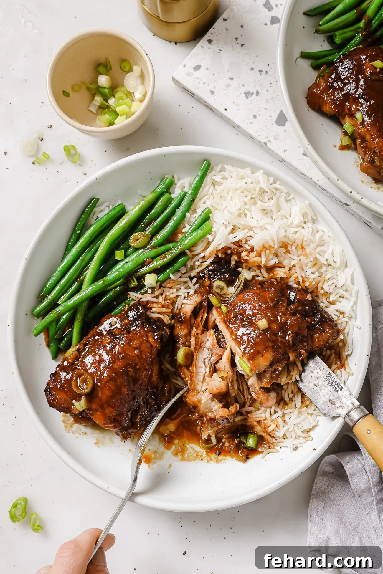 Sweet & Sticky Slow Cooker Chicken 7 Slow Cooker chicken thighs on a white plate with green beans and rice.