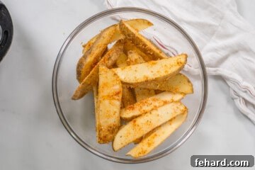 Mixing bowl with potato wedges coated in flour, parmesan, and seasonings.