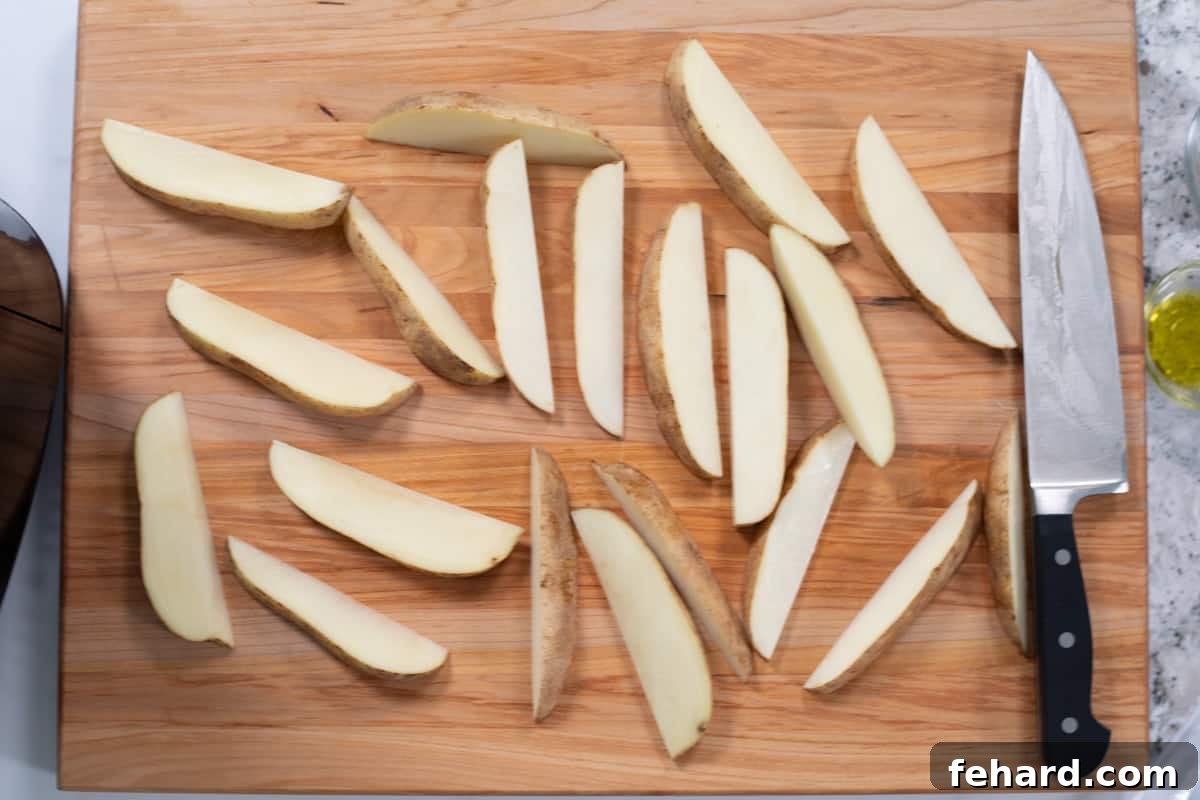 Sliced potato wedges on cutting board next to butcher's knife.