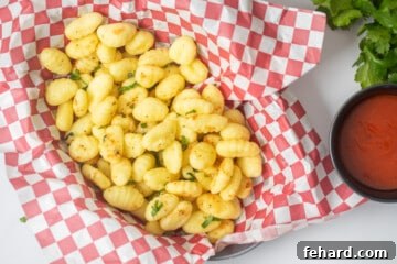 Basket with seasoned, crispy air-fried gnocchi served with marinara on the side.