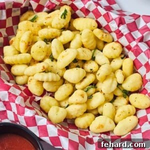 Basket lined with checkered paper filled with Italian seasoned, crispy air-fried gnocchi served with marinara on the side.