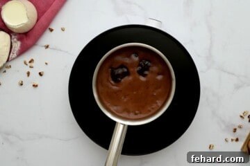 Saucepan with water, butter, and cocoa mixture bubbling gently on a hot plate, creating a rich chocolate base for the cake.