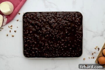 Rich pecan cocoa frosting being poured generously over a warm chocolate sheet cake.