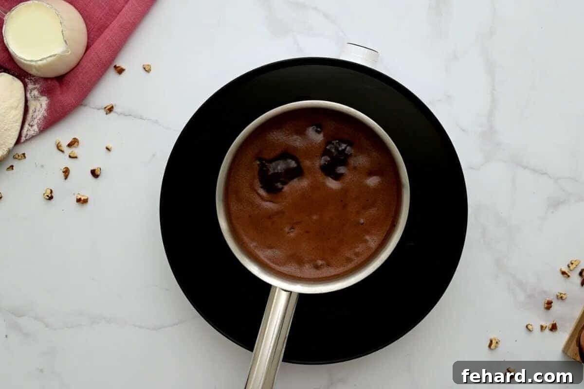 Saucepan with water, butter, and cocoa mixture bubbling gently on a hot plate, forming a rich chocolate base.