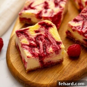 Sliced cheesecake bars on wooden cutting board revealing the raspberry swirl throughout the cheesecake batter.