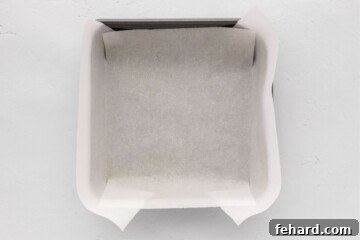 8x8 baking dish lined with parchment paper for lemon cheesecake bars.