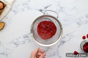 Fine mesh strainer showing removing seeds from raspberry puree.
