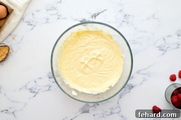 Creamy cheesecake filling in clear mixing bowl.