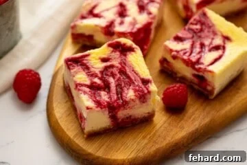 Sliced cheesecake bars on wooden cutting board revealing the raspberry swirl throughout the cheesecake batter.