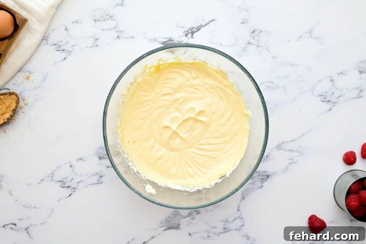 Creamy cheesecake filling in clear mixing bowl.