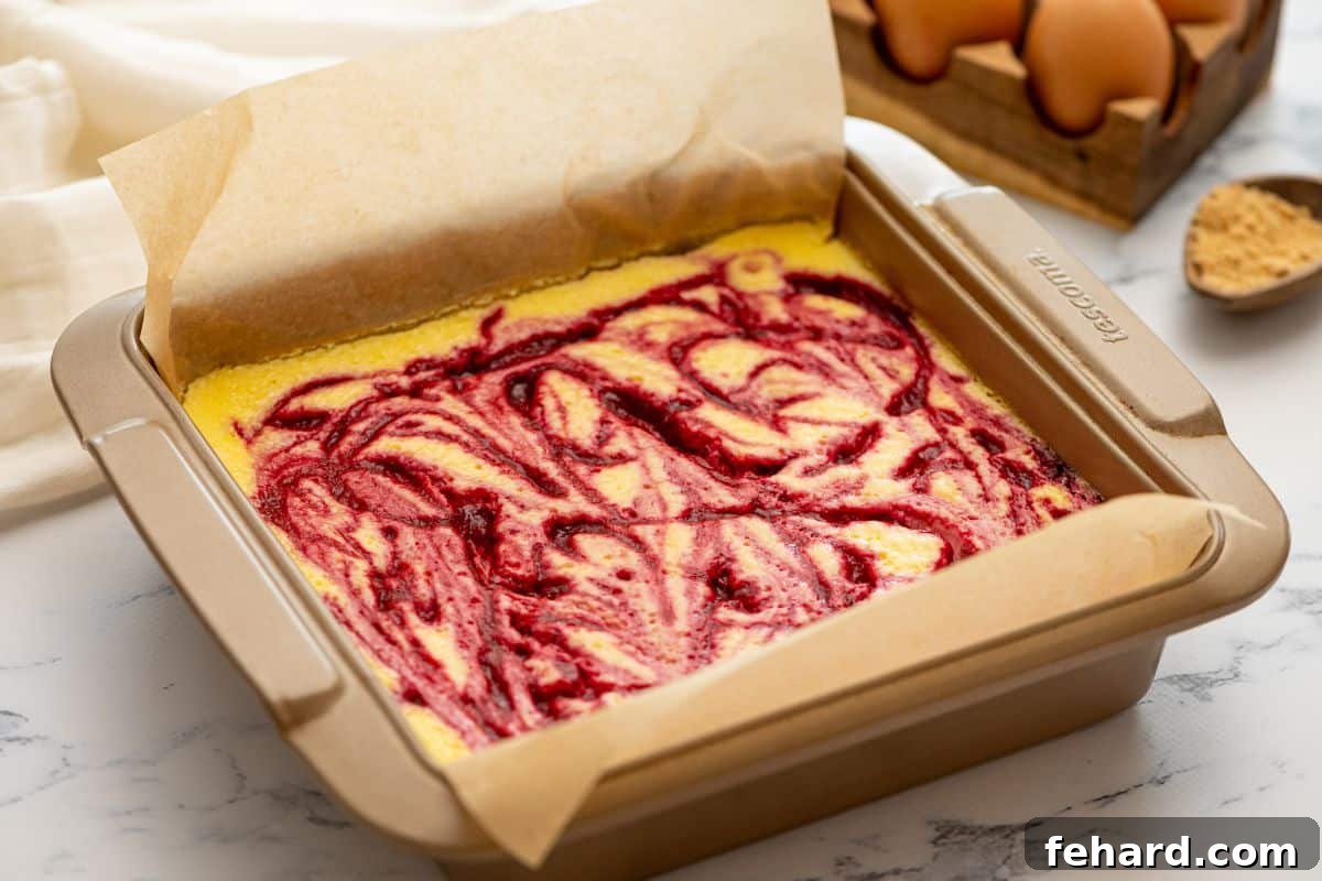 Swirled cheesecake bars in parchment lined baking dish.