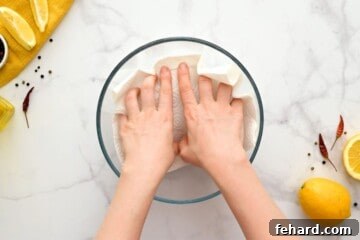 Hands gently patting raw shrimp dry with a paper towel, a crucial step before seasoning.